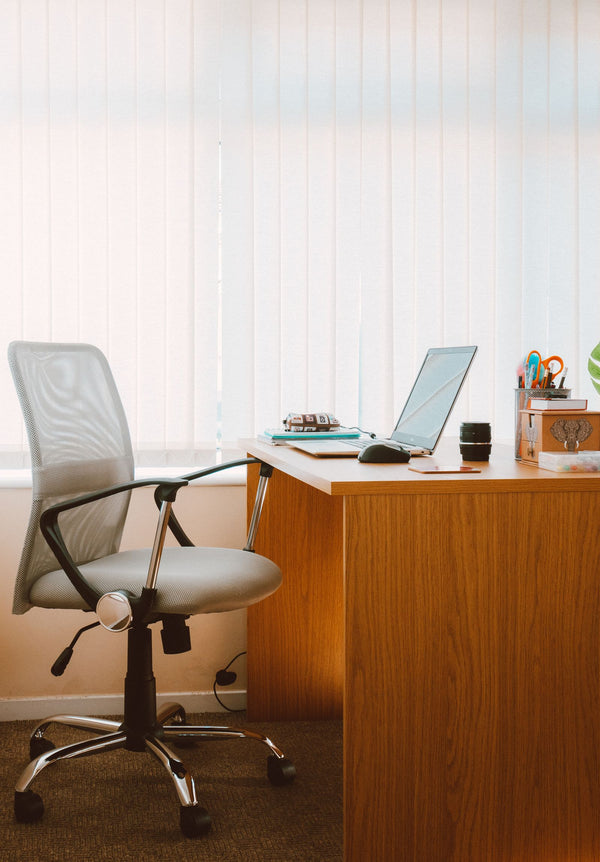 Chaise de bureau ergonomique devant un bureau en bois avec ordinateur portable