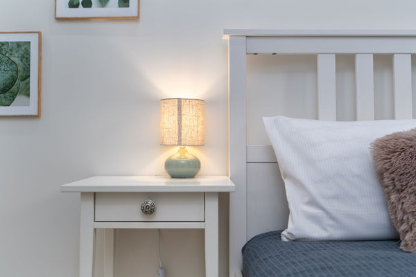 Chambre apaisante le soir avec une lampe de chevet allumée à côté du lit