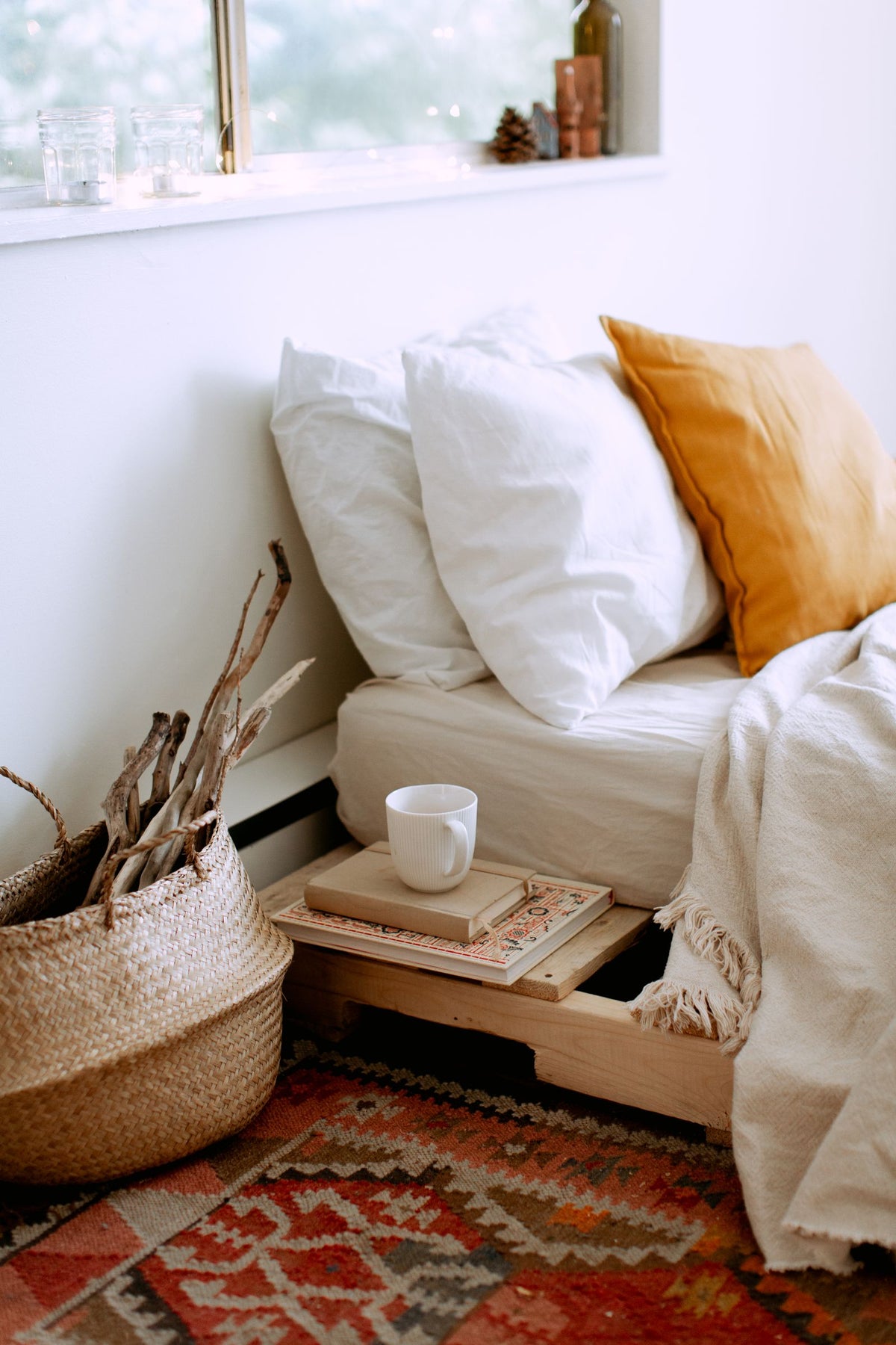 Coin chambre cosy avec lit, oreillers et plaid, lumiere naturelle