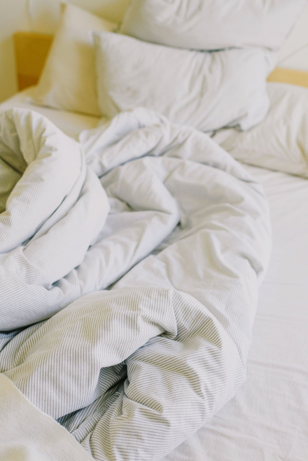 Lit douillet aux draps froissés et oreillers moelleux dans la lumière du jour, idéal pour une sieste
