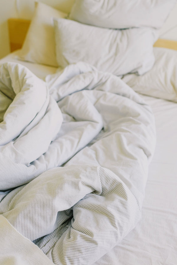 Lit douillet aux draps froissés et oreillers moelleux dans la lumière du jour, idéal pour une sieste