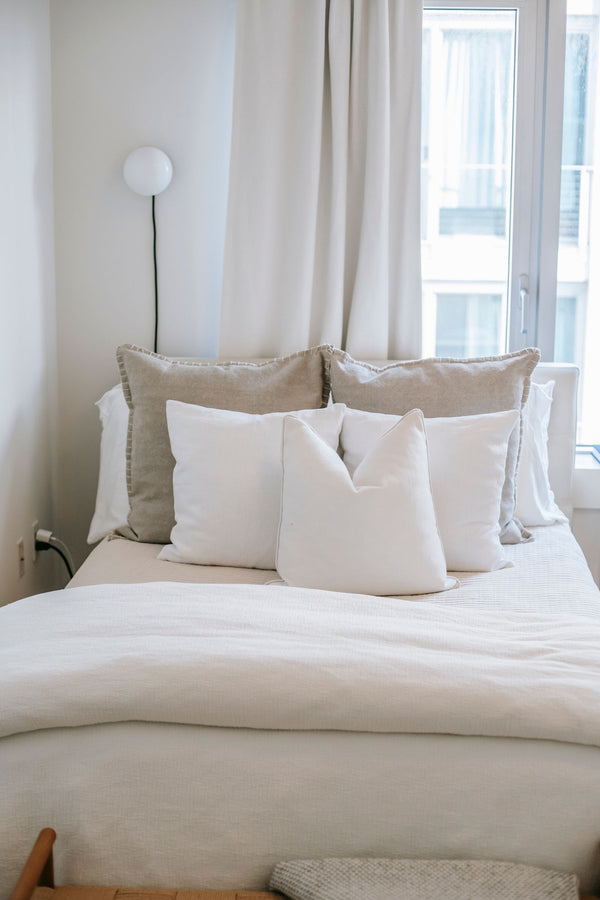 Lit avec oreillers moelleux pres d'une fenetre, chambre lumineuse